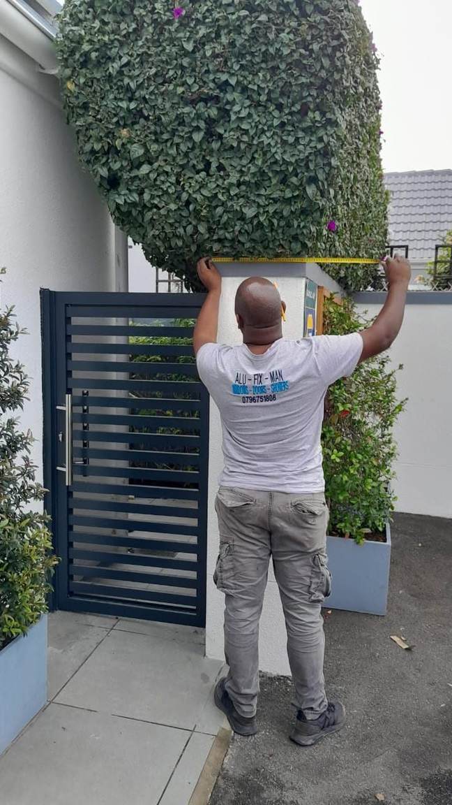 An installer checking the opening above a slatted aluminium gate